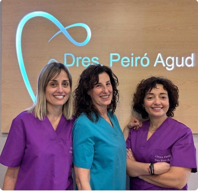 Tres profesionales de Clínica Dental Peiró Agud frente al logotipo de la clínica